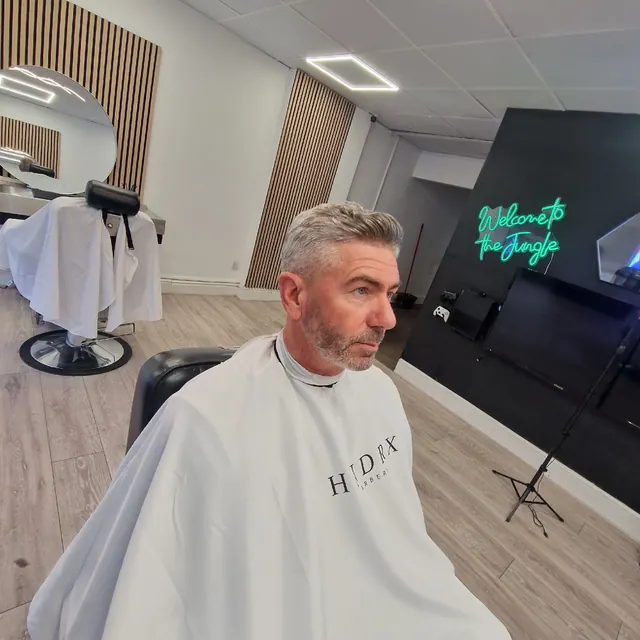 In the chair at HNDRX Barbers, with the neon sign behind